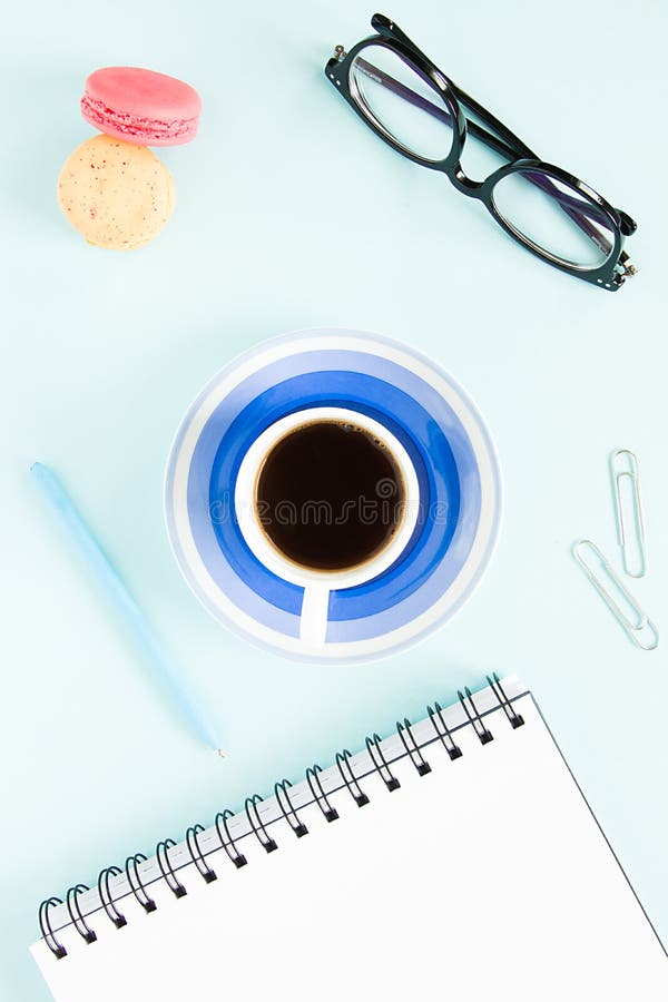Makron en kopp av svart kaffe, en öppen anmärkning med den vita sidan, penna, exponeringsglas på en pastellfärgad blå bakgrund Bi fotografering för bildbyråer