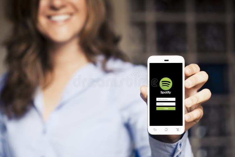 MALAGA, SPAIN - APRIL 26, 2015: Smiling woman holding a mobile phone with Spotify Music App in the screen.