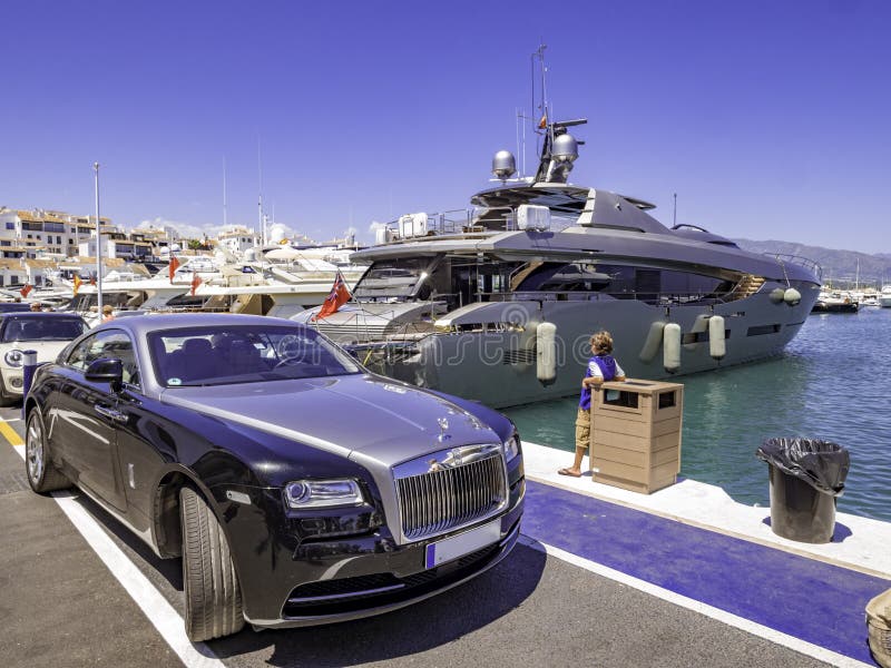 Rolls-Royce car next to a huge yacht in Puerto Banus, a luxury harbour and marina in Marbella
