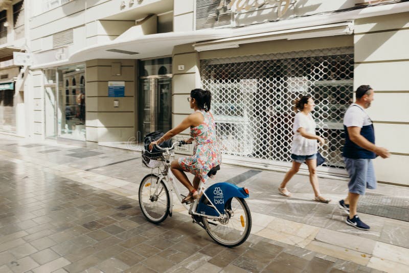 MALAGA, SPANJE - September tweede, 2018: Vrouw die een fiets berijden tijdens een reis in het stadscentrum van Malaga, Spanje stock foto MALAGA, SPANJE - September tweede, 2018: Vrouw die een fiets berijden tijdens een reis in het stadscentrum van Malaga, Spanje stock foto