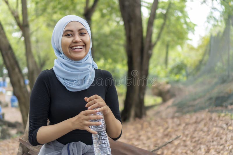 Malay Muslim lady wearing hijab outdoor resting and drink water