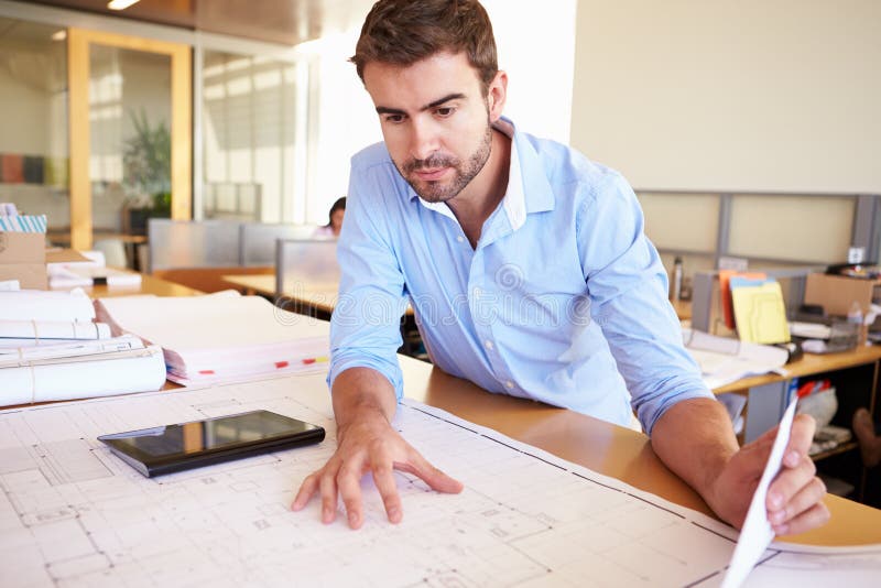 Male Architect With Digital Tablet Studying Plans In Office stock photography
