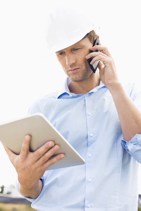 Male architect with digital tablet using cell phone at site stock photos