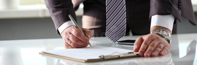 Male arm in suit and tie fill form clipped to pad. Letter, business.