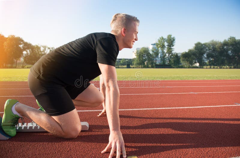 Male athlete on starting position at athletics running track. Outdoors, person.