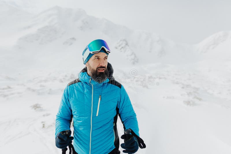 Muž backcountry lyžař pěší na vrchol zasněženého vrcholu v Nízkých Tatrách na Slovensku.