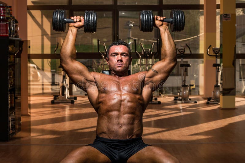 Male bodybuilder doing shoulder press whit dumbbell stock photos Male bodybuilder doing shoulder press whit dumbbell stock photos