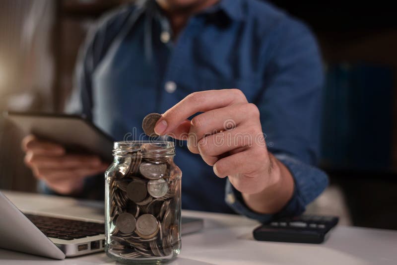 Male businessman holding coins putting in glass with using  calculator to calculate concept saving money.