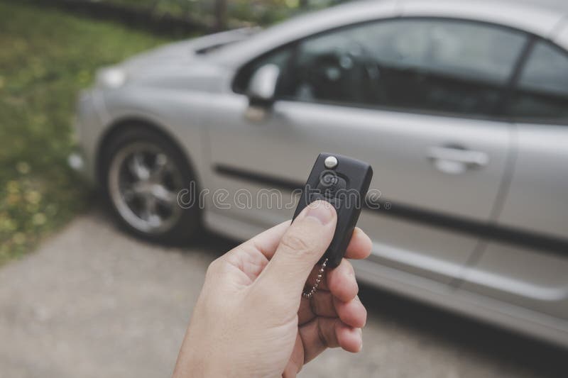 Male car owner switches off the alarm system and unlocks the doors of the car using remote control keys on a parking stock photography Male car owner switches off the alarm system and unlocks the doors of the car using remote control keys on a parking stock photography