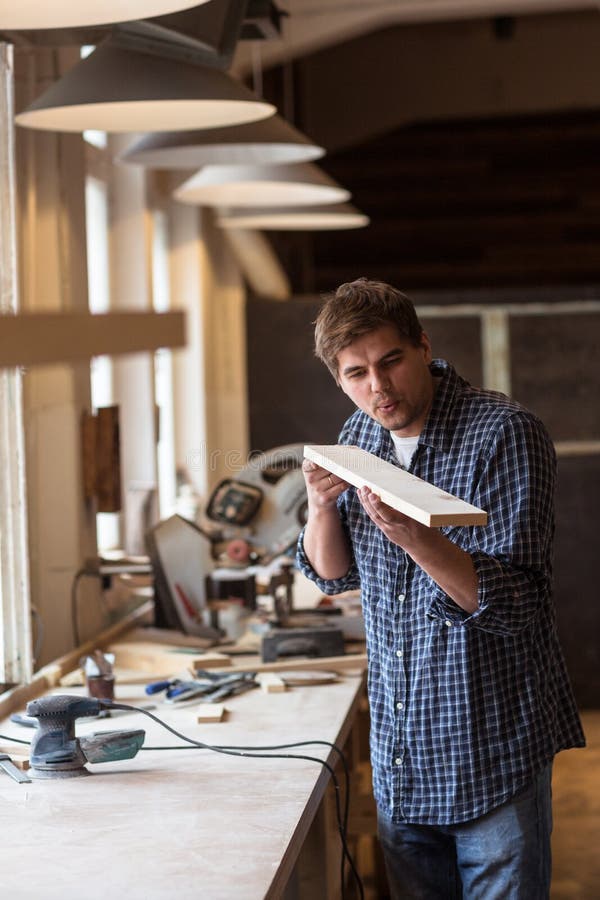 Male carpenter in carpentry workshop blows chips with wooden boa royalty free stock photo Male carpenter in carpentry workshop blows chips with wooden boa royalty free stock photo