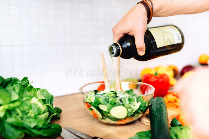 Male chef preparing salad, pouring virgin olive oil on vegetables royalty free stock photography Male chef preparing salad, pouring virgin olive oil on vegetables royalty free stock photography