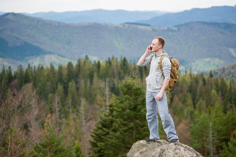 Male climber with brown backpack on the peak of rock stock photography Male climber with brown backpack on the peak of rock stock photography