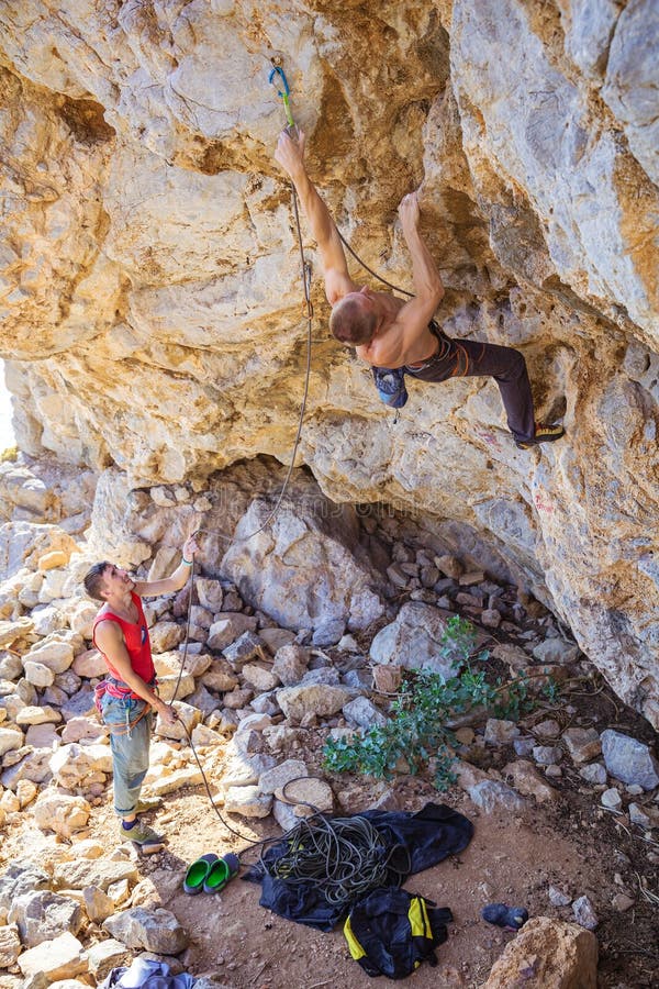 Male climber clipping rope, his partner belaying