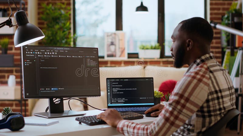 Male coder works from home typing code on a laptop in a modern living room stock photography