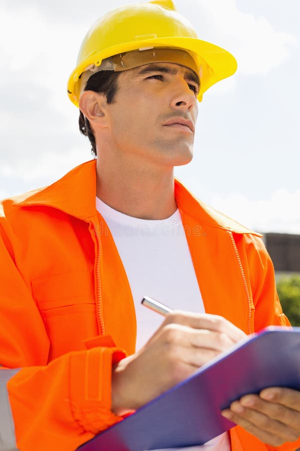 Male construction worker with clipboard looking away outside stock photos