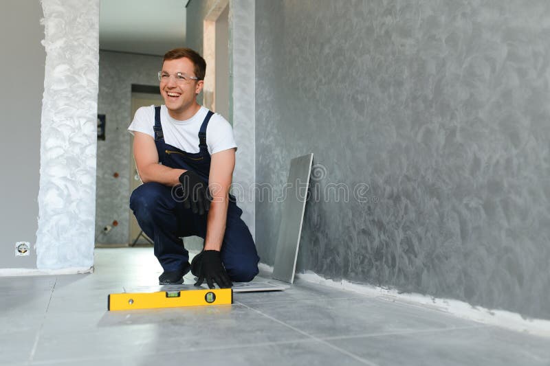 A male construction worker installs a large ceramic tile royalty free stock images