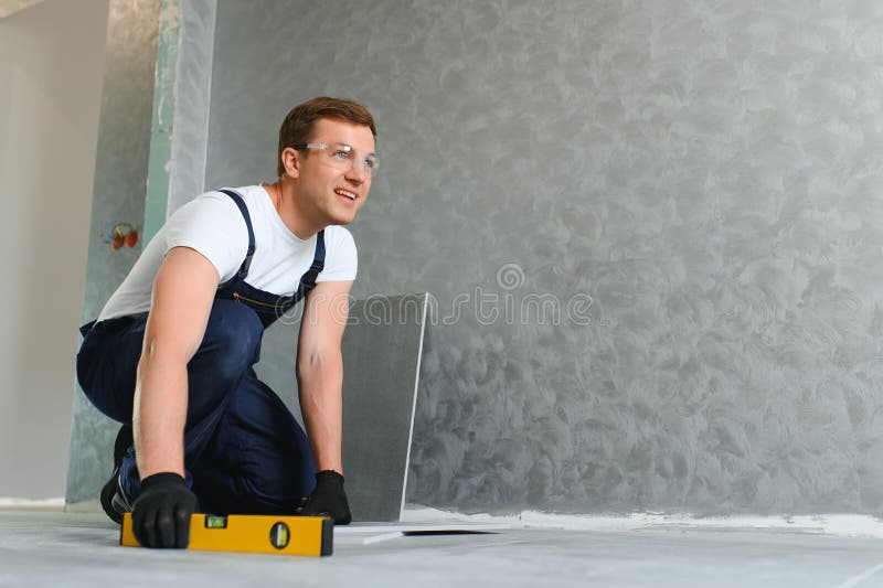 A male construction worker installs a large ceramic tile stock images