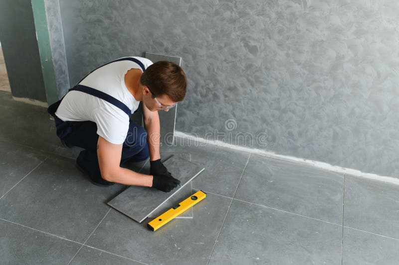 A male construction worker installs a large ceramic tile royalty free stock photography
