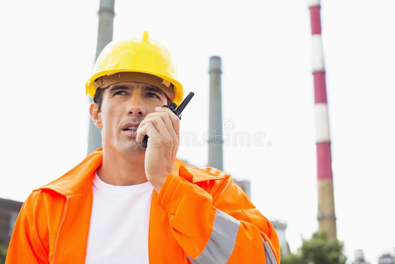 Male construction worker wearing reflective workwear communicating on walkie-talkie at site royalty free stock photos