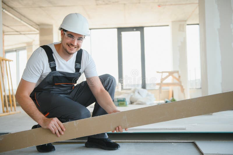 Male construction worker wearing uniform Install gypsum ceiling inside the house and building stock photos
