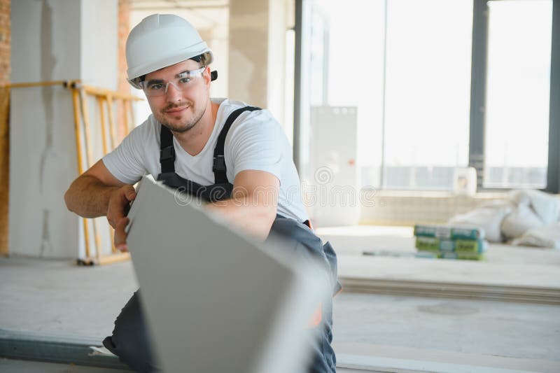 Male construction worker wearing uniform Install gypsum ceiling inside the house and building stock image