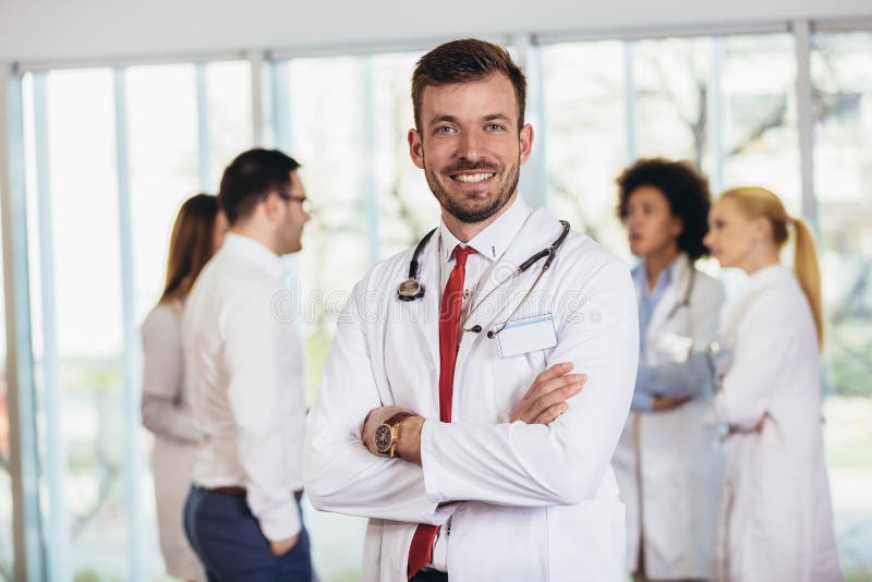 Doctor with colleagues in background, doctor looking at camera with emergency team in background royalty free stock photography Doctor with colleagues in background, doctor looking at camera with emergency team in background royalty free stock photography