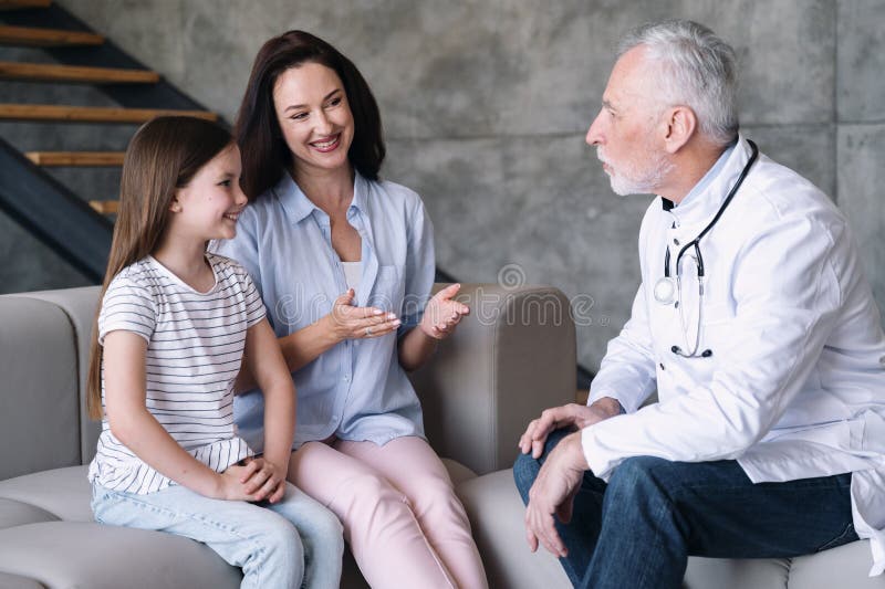 Medic masculin sau pediatru ascultând cu atenție copilul și mama royalty free stock images