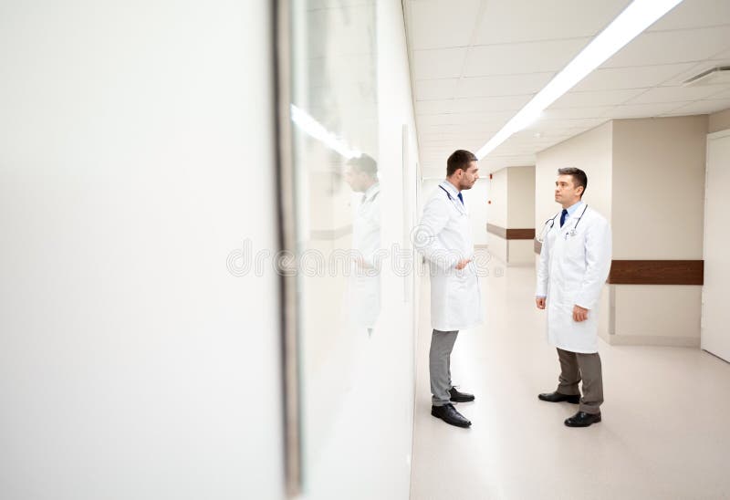 Male doctors talking at hospital corridor