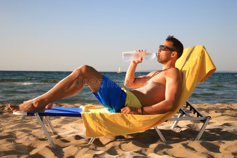 Handsome male drinking water at the beach