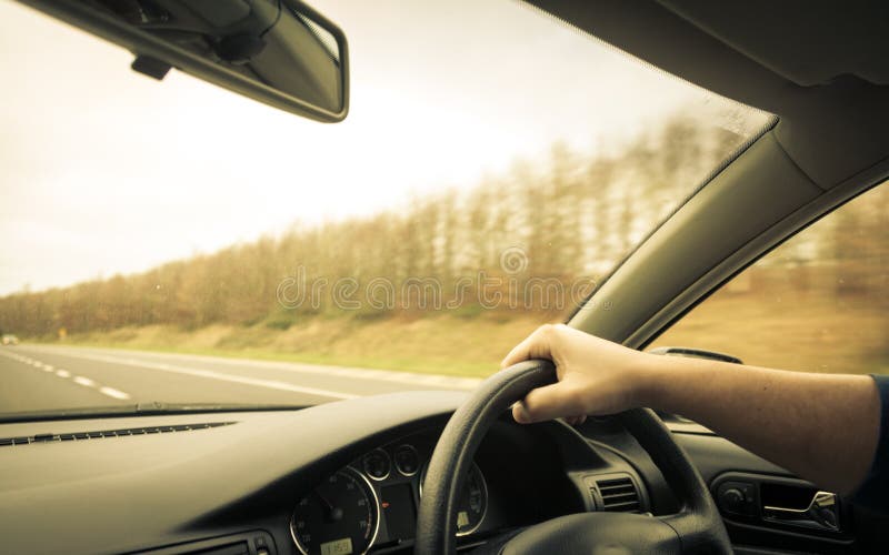 Male Driver Hands on Steering Wheel of a Car and Road Stock Photo