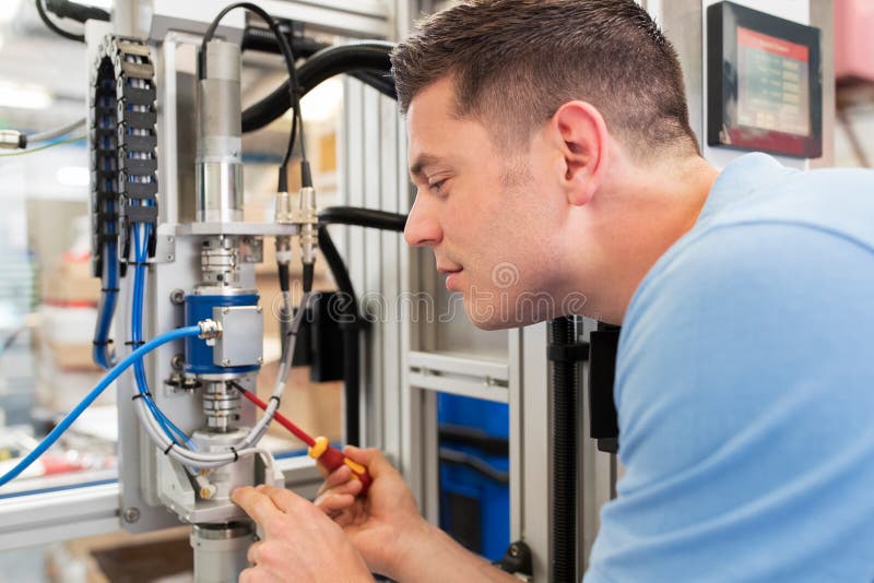 Male Engineer Working On Machine In Factory stock images