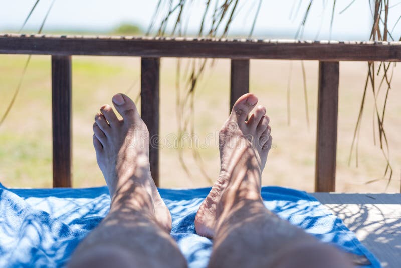 Male Feet On Lounge In Bungalow Sea View