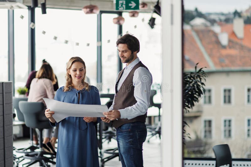 Two collegues talking about project document, standing in modern office. stock images