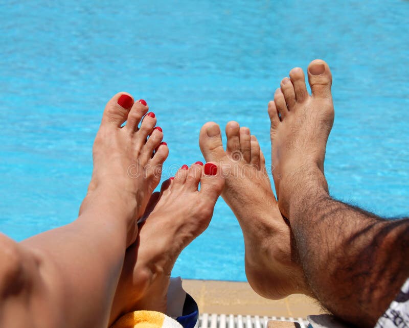 Male and female feet by blue swimming pool