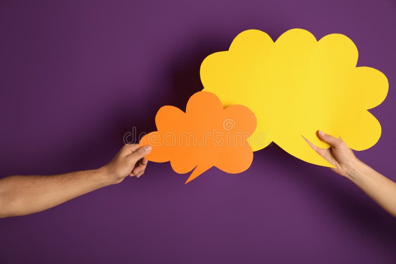Male and female hands with speech bubbles on color background stock photo