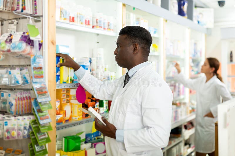 Male and female pharmacists working in salesroom of drugstore. They putting drug packages in order. Male and female pharmacists working in salesroom of drugstore. They putting drug packages in order.