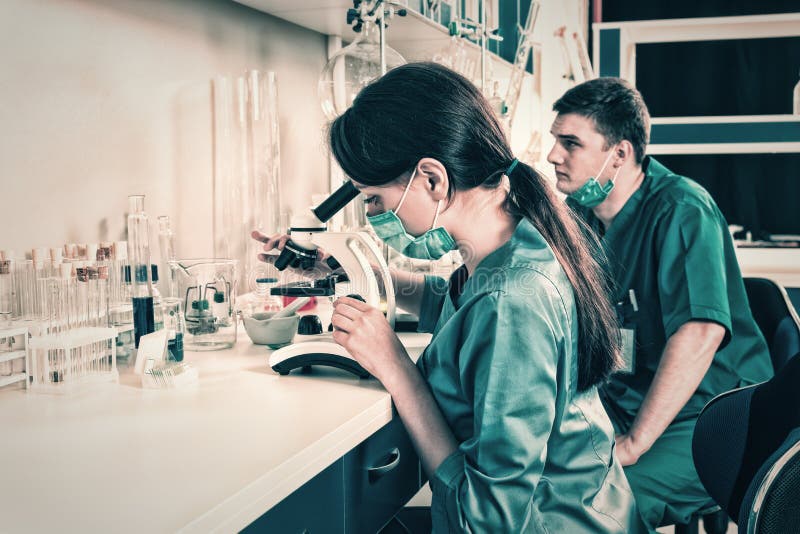 Male and female scientists in uniform is looking through a micro royalty free stock photo Male and female scientists in uniform is looking through a micro royalty free stock photo