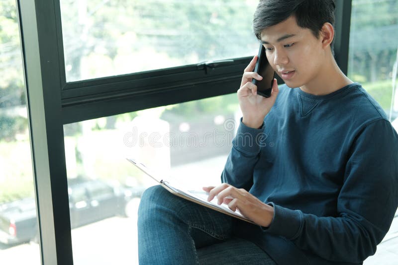 Male freelancer falando com um celular inteligente no escritório homem freelance asiático empresária trabalhando com documento ne foto de stock royalty free Male freelancer falando com um celular inteligente no escritório homem freelance asiático empresária trabalhando com documento ne foto de stock royalty free