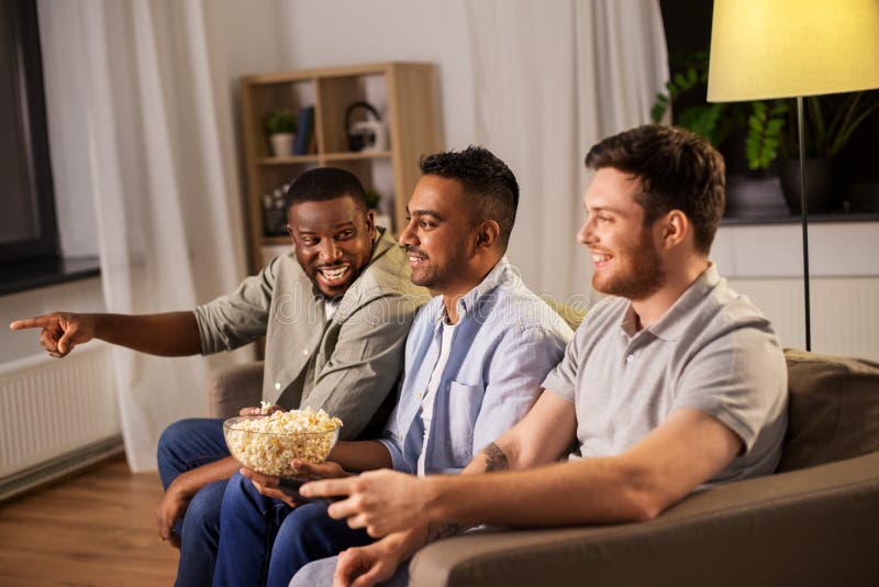 Male friends with popcorn watching tv at home royalty free stock images Male friends with popcorn watching tv at home royalty free stock images