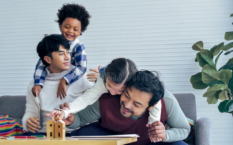 Male gay taking care adopted children who are happy diverse little Caucasian girl and African boy, hugging, playing toys together.