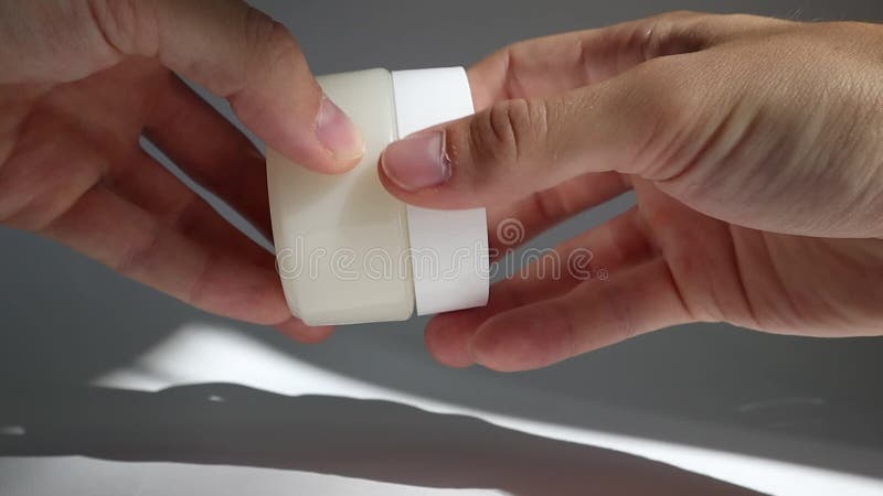 Male hand close White plastic tube with round cap on white background with shadows. Front view for your design. facial cosmetic pr