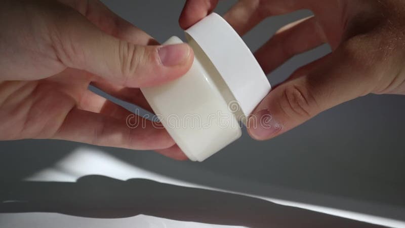 Male hand close White plastic tube with round cap on white background with shadows. Front view for your design. facial cosmetic pr