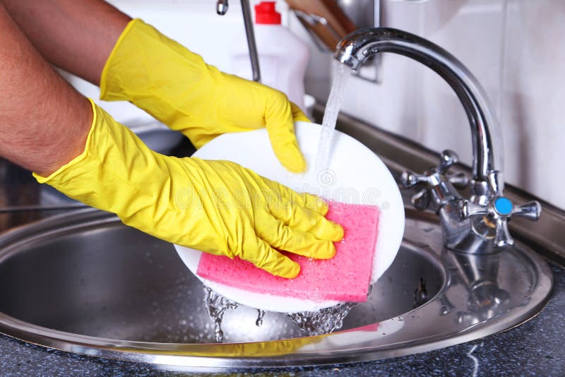 Male hand in gloves with sponge washing dish stock image