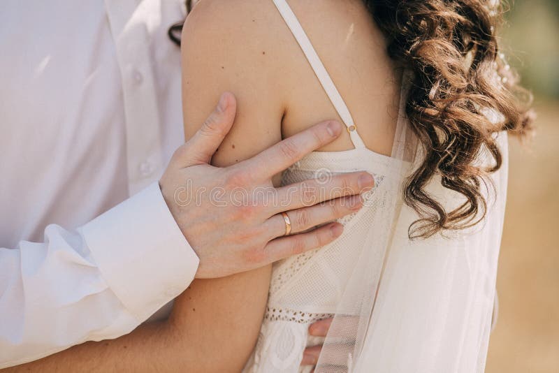 Male hand of the groom close-up with a gold ring hugging the bride in a wedding dress stock image Male hand of the groom close-up with a gold ring hugging the bride in a wedding dress stock image
