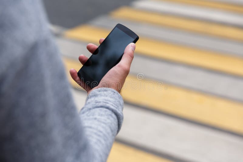 Male hand holding smartphone with blank screen on pedestrian crossing royalty free stock images Male hand holding smartphone with blank screen on pedestrian crossing royalty free stock images
