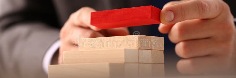 Male hand holds red wood block of stair.