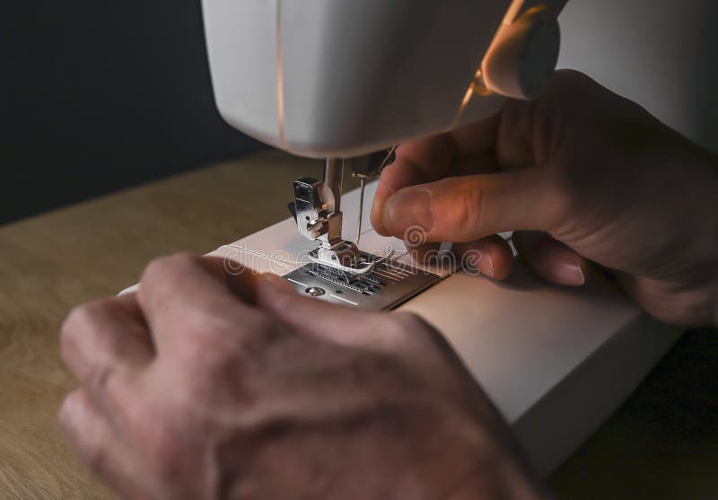 Male Hand Inserting Thread into Needle of Sewing Machine Stock Image