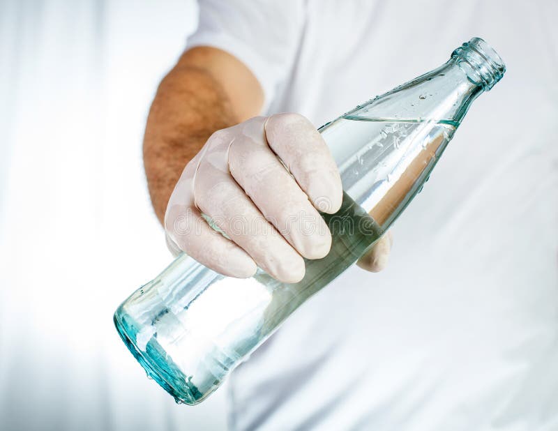 Male Hand in Latex Glove Holding Glass Bottle of Water Stock Photo