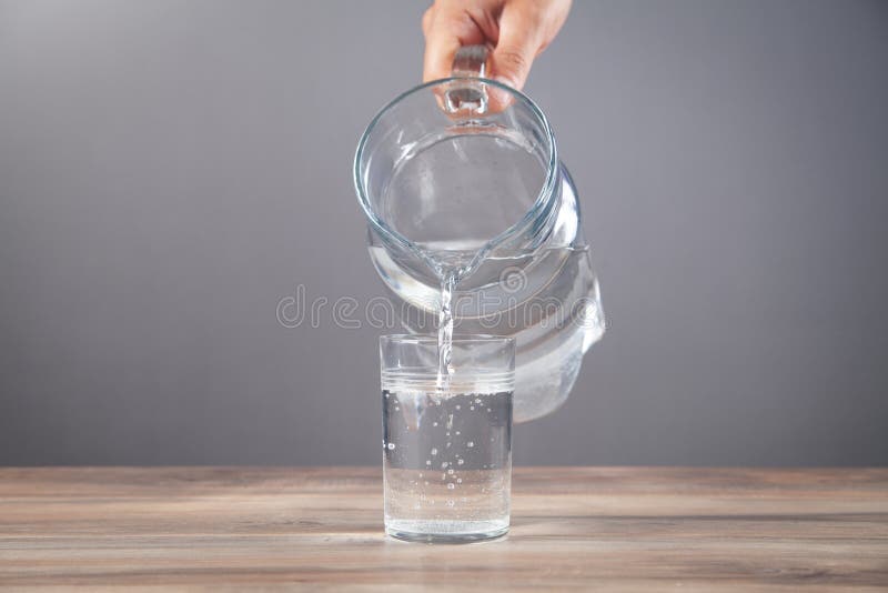 Hand pouring water from glass pitcher Stock Photo