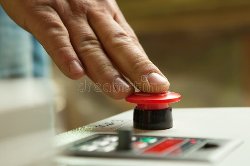 Male hand pushing emergency stop button.